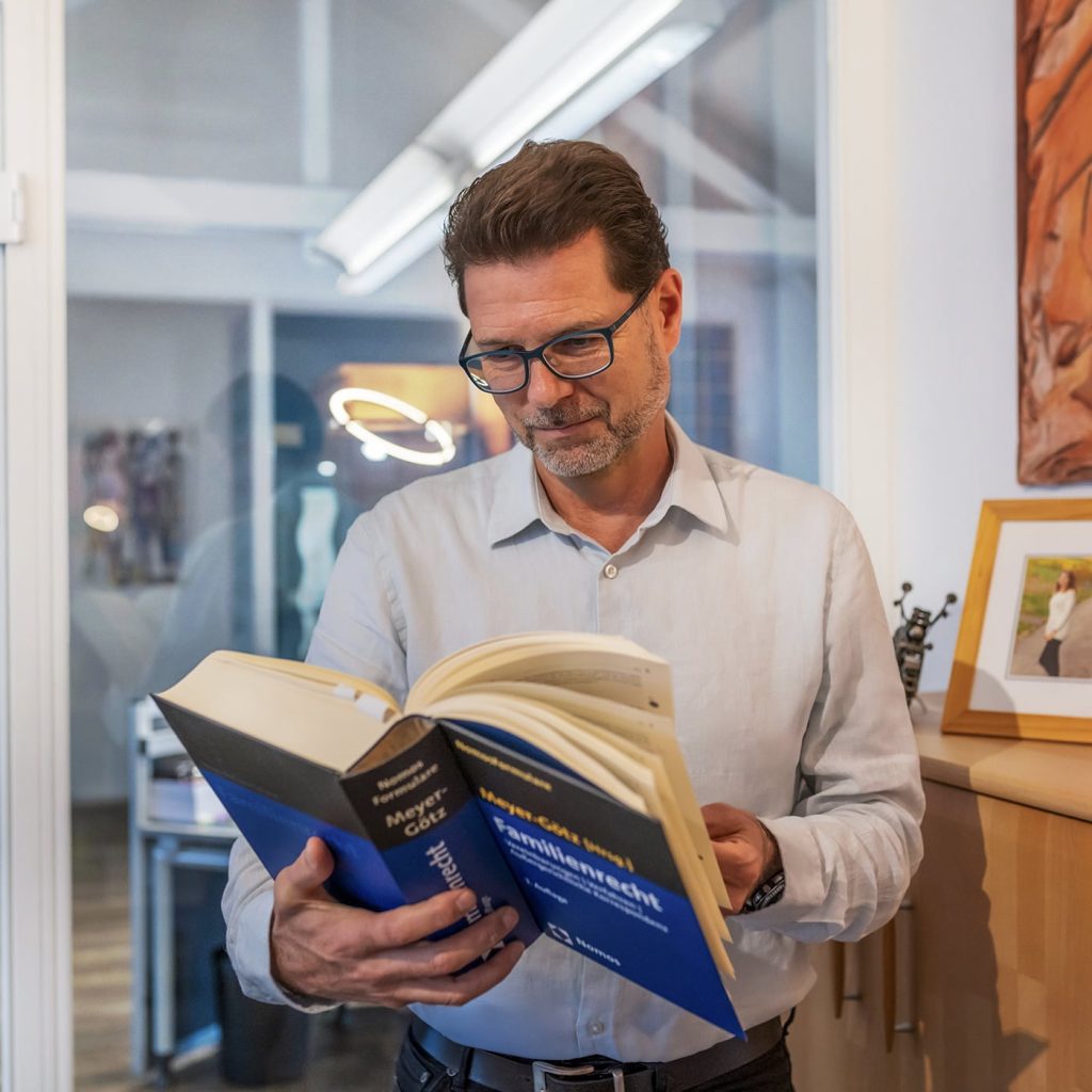 Jürgen Fuchs liest ein Fachbuch zum Familienrecht – sorgfältige Vorbereitung und ausgewiesene Expertise.